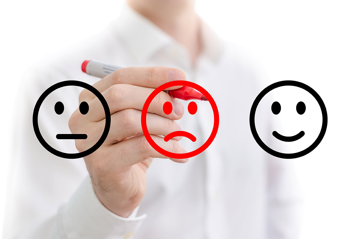 Manage negative online reviews: An image showing review emojis: happy, sad, and neutral where the sad face is highlighted in red ink