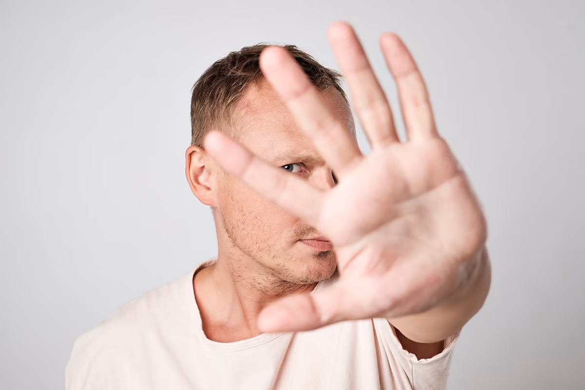 overcoming objections: a man with a mad face and showing hand a gesture to stop