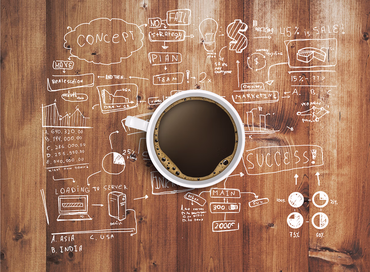 a cup of black coffee placed on top of a table full of planning doodles