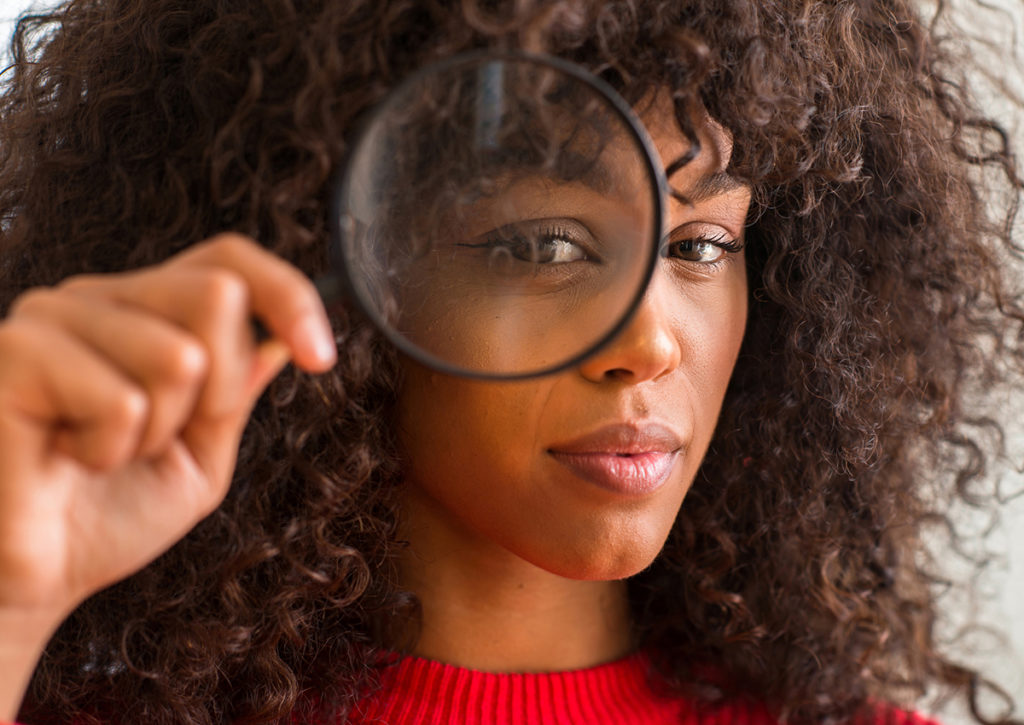 You'll improve your visibility: a woman holding a magnifying glass to her right eye